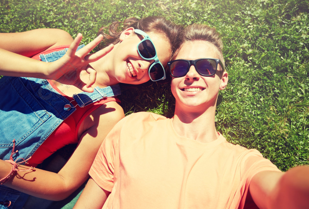 在夏天采取自拍照快乐的少年情侣,夏天草地上采取自拍照