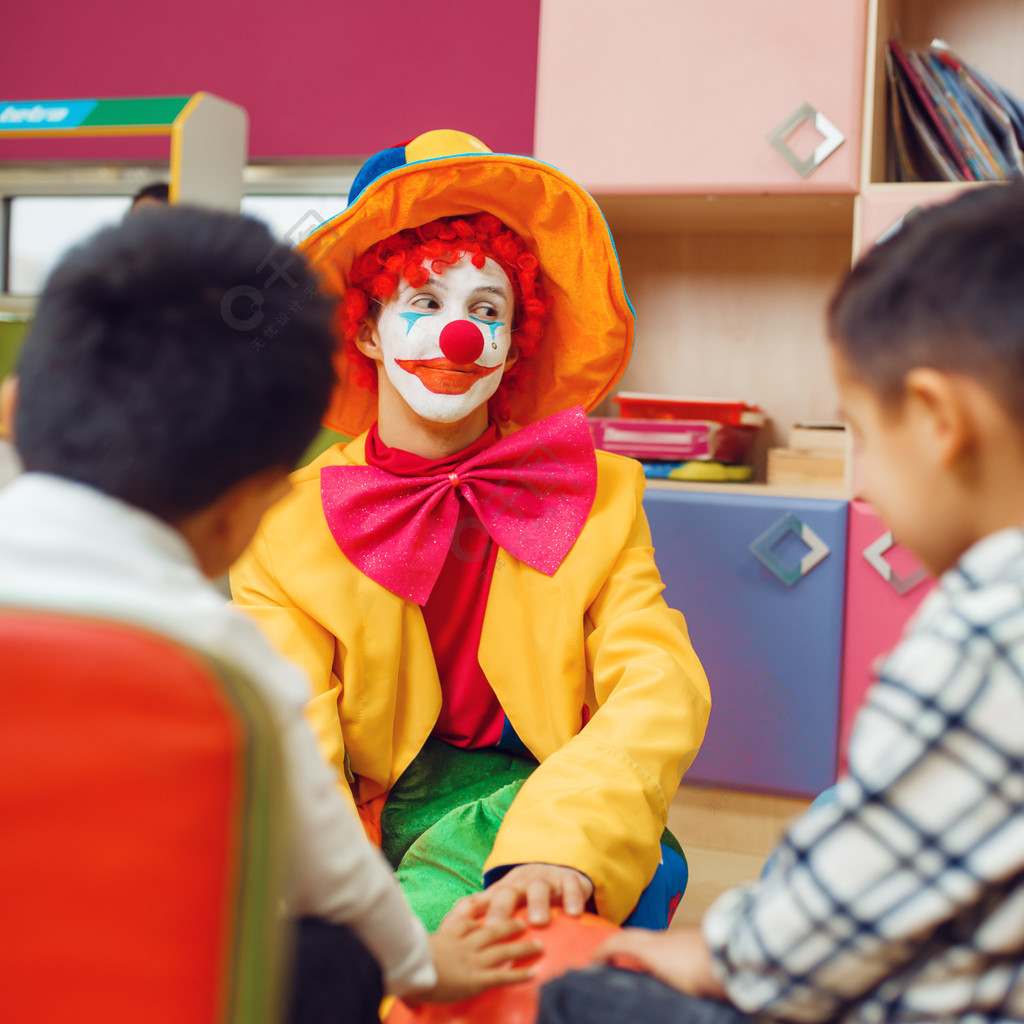 滑稽的小丑和開朗的孩子一起玩慶祝在遊戲室嬰兒假期在操場上的生日