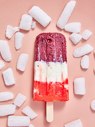 在一根棍子的果子自创色的冰淇凌有在桃红色背景的冷的冰块的冷甜点顶视图在一根棍子的多彩多姿的莓果冰淇凌有在桃红色背景的冰块的顶视图