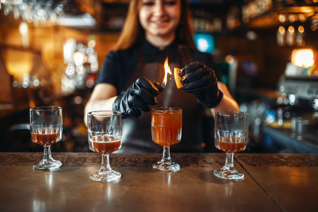 飲料的製備在酒吧裡的酒吧櫃檯工作的男服務員女調酒師用火製作雞尾酒