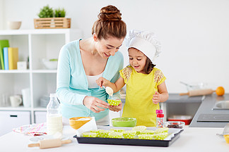 家庭，烹饪，烘烤和人们观念-幸福的母亲，与杯形蛋糕衬<i>里</i>和小女儿用勺子浇面糊和在家做松饼的厨房幸福的母亲和女儿在家<i>里</i>烤蛋糕幸福的母亲和女儿在家<i>里</i>烤蛋糕