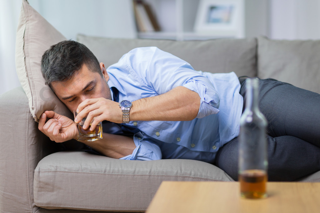 酒精中毒酒精成瘾和人们观念男性酒精躺在沙发上喝威士