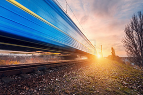 在铁轨的高速蓝色旅客列车在日落的行动通勤火车模糊火车站铁路旅行，铁路旅游工业景观秋季的夜晚概念