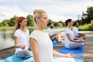 健身，运动，瑜伽和健康的生活方式的概念— —一群人在河或湖泊位上的<i>莲</i><i>花</i>姿势打坐