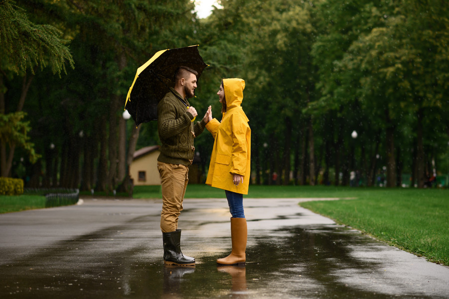 2愛情侶撐著雨傘,下雨天在夏日公園浪漫約會.