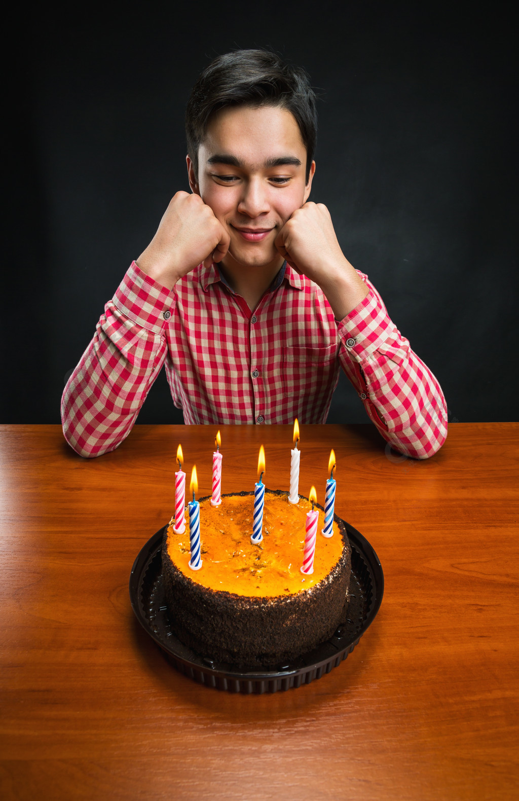 生日男孩和一个蛋糕与蜡烛在桌上伤心的生日男孩