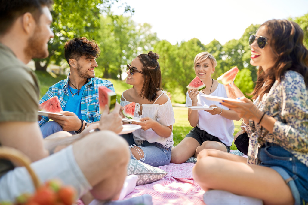 友誼休閒和食品的概念群快樂的朋友在夏天公園野餐吃西瓜快樂的朋友在