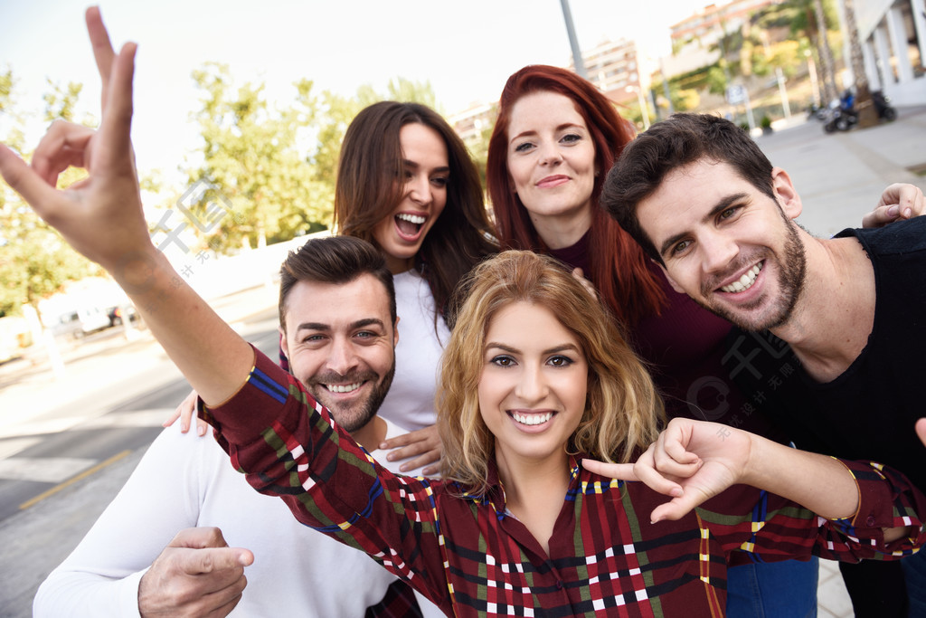 小组朋友在都市背景中的采取selfie五个年轻人穿着便服