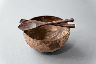 回收，餐具和生态友好的概念-接近椰子碗用棕色木勺和叉子在桌子上椰子碗，木汤匙和叉子的特写