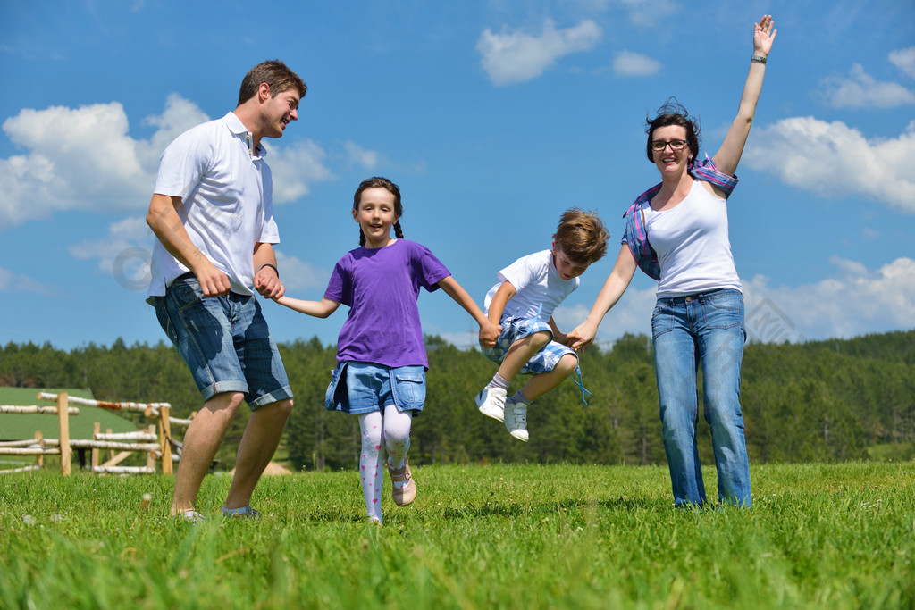 幸福的年轻家庭,与他们的孩子们玩得开心,在大自然中户外放松与背景中