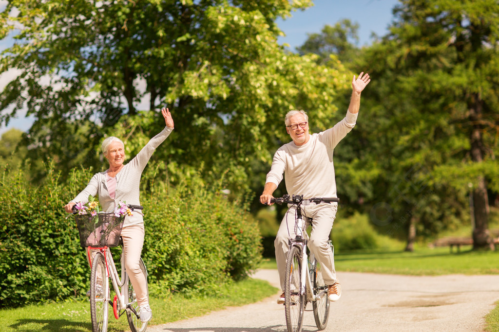 活跃的老年人们和生活方式的概念快乐的年长夫妇骑自行车挥舞着的手在