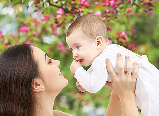 家<i>庭</i>和母性的概念— —幸福微笑的年轻母亲，与小宝宝在天然泉水樱花背景母亲与婴儿在春天花园的背景