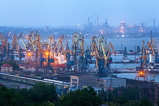 海商业口岸在反对运转的钢<i>铁</i>生产厂的晚上在马里乌波尔，乌克兰工业视图货物运输船与黄昏工作起重机桥海港货运港口，物流