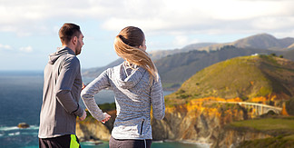 <i>健</i>身，体育，人们和<i>健</i><i>康</i>的<i>生</i>活<i>方</i>式的概念— —幸福的夫妇，在加利福尼亚州背景大瑟尔海岸上运行的比克斯比河大桥幸福的夫妇，在户外跑步幸福的夫妻在户外跑步