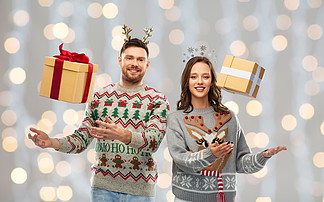 人和假日概念-愉快的加上<i>画</i>象在丑恶的毛线衣<i>党</i>的圣诞节礼物在欢乐光背景幸福的夫妇，在圣诞毛衣和礼品盒