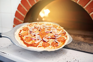 食品，意大利厨房，烹饪，烘烤和烹饪概念-在比萨店将披萨放在烤箱里<i>剥</i><i>皮</i>将比萨饼放在比萨店的烤箱中去<i>皮</i>