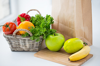 烹饪，饮食，素食和健康饮食概念-在家中厨房桌子上有新鲜成熟多汁的蔬菜，蔬菜和水果的<i>篮</i>子的特写