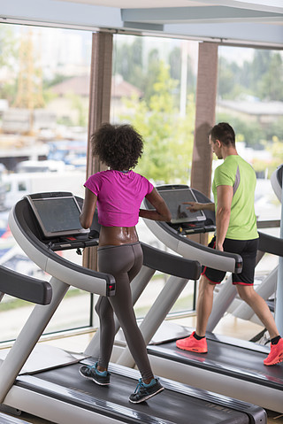 年轻人在现代健身房的跑步机上锻炼有氧运动