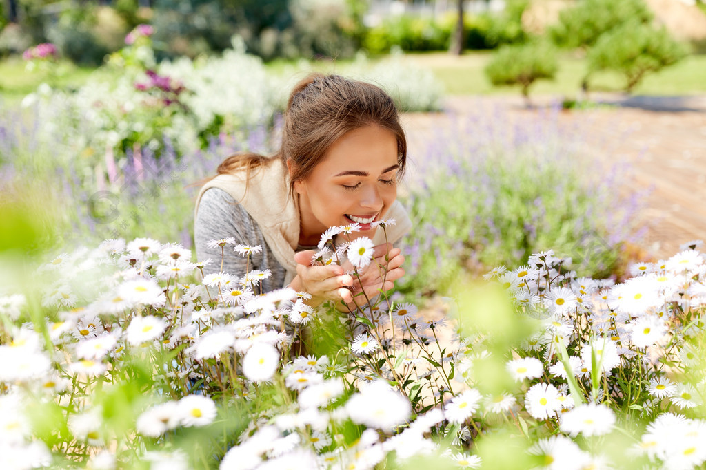 园艺和人们观念愉快的少妇嗅到的春黄菊在夏天庭院开花幸福的女人闻到