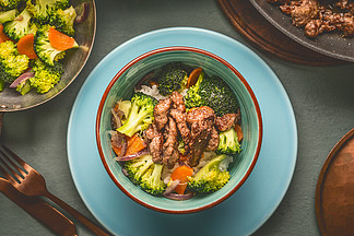 在碗里用牛肉，米饭，蒸的蔬菜健康均衡的营养餐的特写：西兰花和胡萝卜配盘子和餐具，顶视图