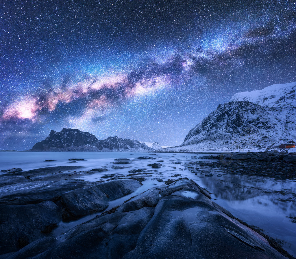 挪威覆盖的高山和岩石的海滩在冬天景观与蓝色的星空,水,石,雪岩石