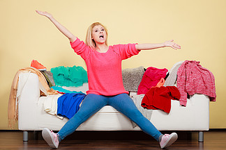 服装困境概念女人<i>不</i><i>知</i>道穿什么衣服坐在一堆堆衣服的凌乱沙发上