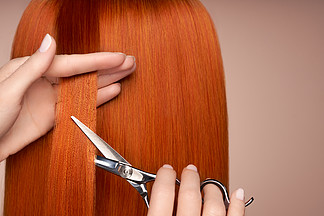 美发师用剪刀剪长长的红头发美发沙龙，发型师<i>护</i><i>理</i>和美容美发产品染过的头发