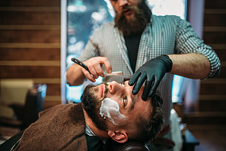 理发师在理发店用剃刀剃掉客户的胡<i>须</i>理发师在理发店用剃刀剃掉客户的胡<i>须</i>