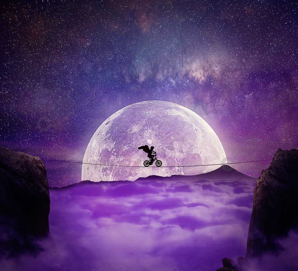 有天使翼的男孩在骑自行车的峡谷的一根导线的平衡自我克服和冒险的概念云层的满月夜背景