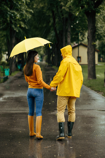 在雨天愛加上走在 i>夏 /i>天公園的傘男人和女人在人行道上,雨溼在