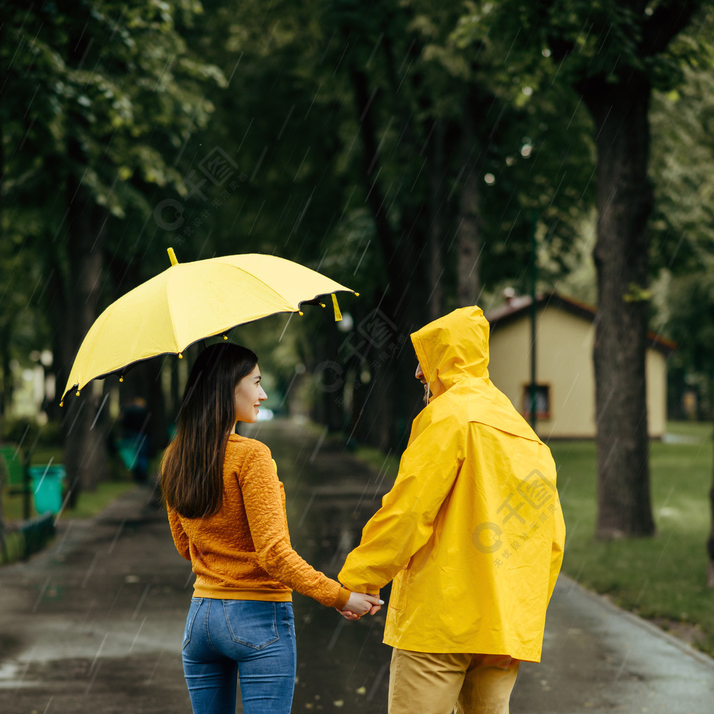 伞男人和女人在人行道上,雨湿在巷子里的橡胶靴爱与伞走在雨天的情侣
