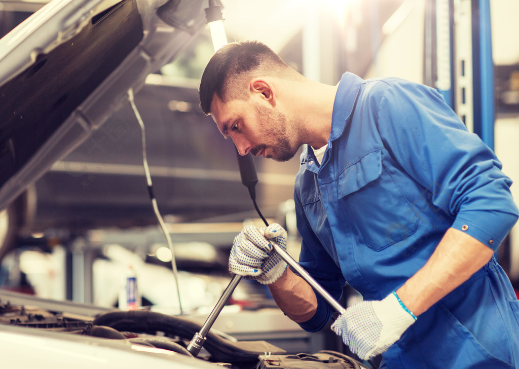 汽車服務維修保養和人的概念用扳手和燈在車間工作的汽車修理工用扳手