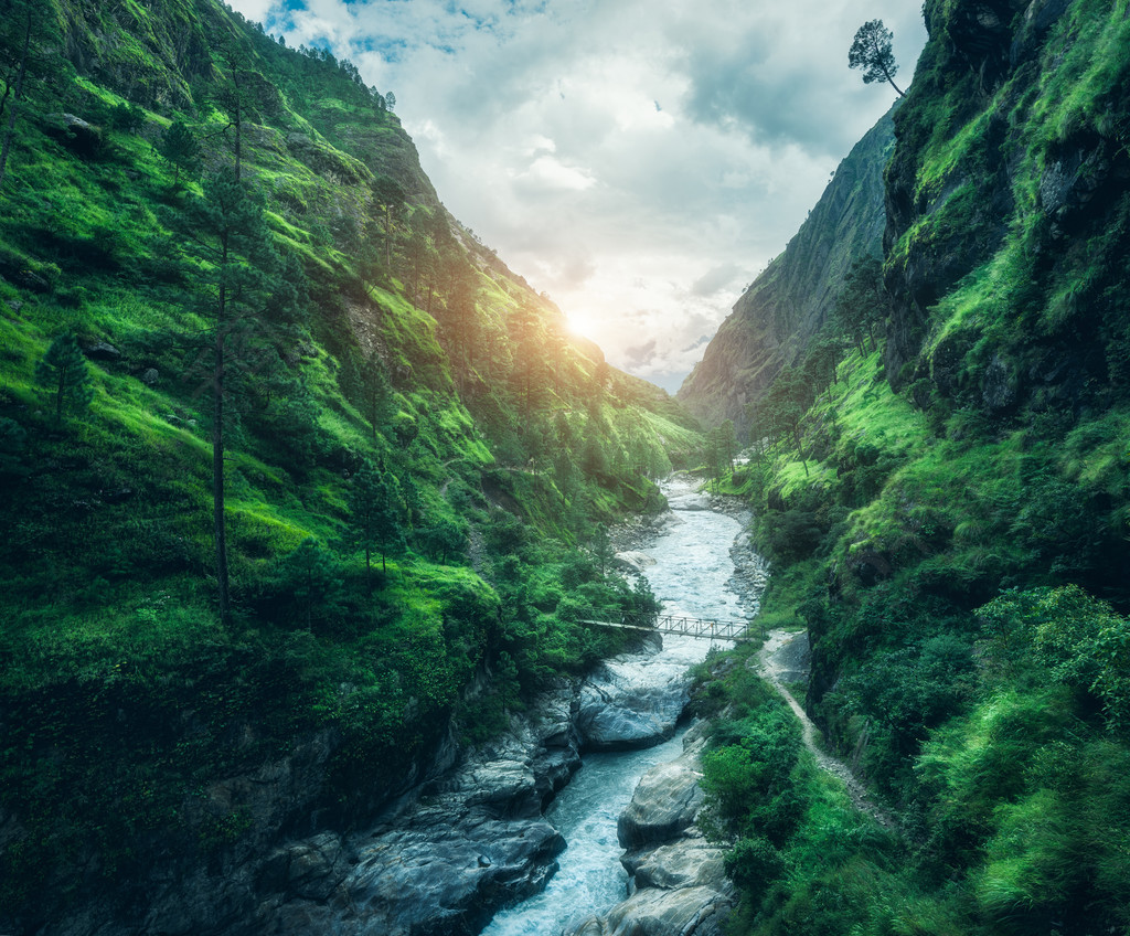 美麗的山日落覆蓋綠草景觀與高山峽谷河流草地和森林天空有云夏季在