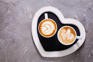 在两杯热奶咖啡的拿铁艺术在心脏形状盘子上早上快<i>乐</i><i>情</i><i>人</i>节<i>情</i>侣爱的<i>情</i>侣卡布奇诺咖啡