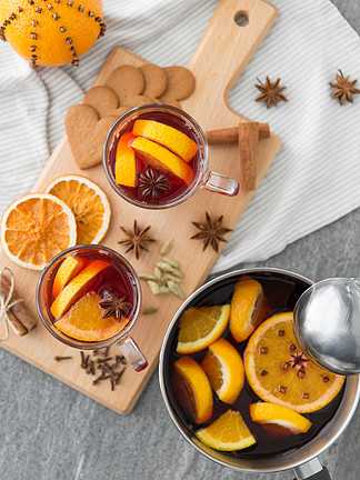圣诞节和季节性饮料的概念— —用热甜酒，橙片，<i>香</i>料和钢包在灰色的背景上的锅热热红酒，橙片和<i>香</i>料的锅