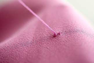 十字绣，针线活和剪裁概念-在粉红<i>色</i>的织物上缝线在粉红<i>色</i>的织物上的十字绣线