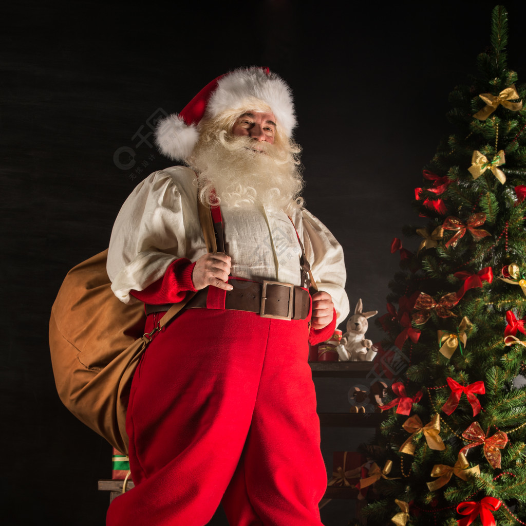 真正的圣诞老人,背着大袋子装满礼物,在家附近圣诞树上的全长画像