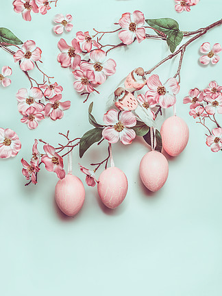 <i>复</i>活节柔和的粉红色布局与垂悬的鸡蛋和绿松石背景上的装饰开花