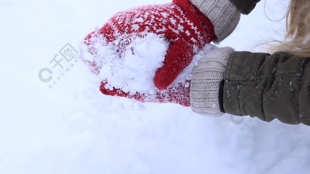 关闭在做雪球的红色被编织的手套的女性手在白色雪背景在拿着自然白色