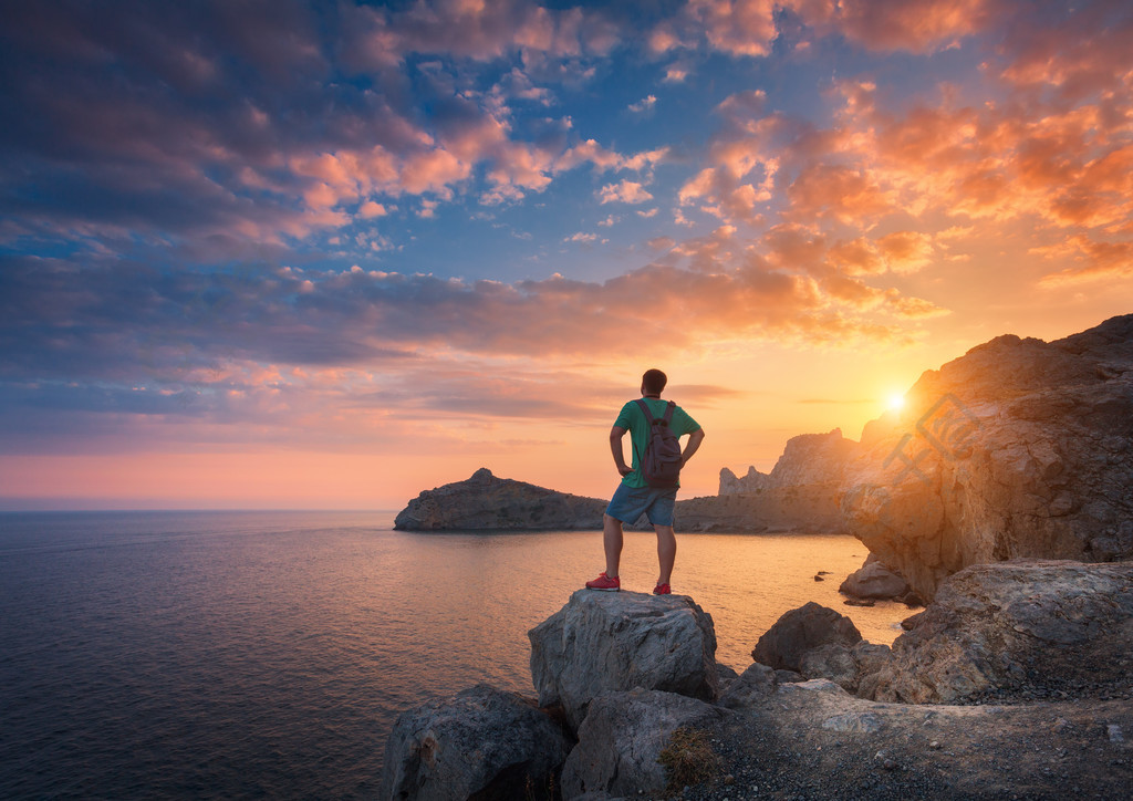 的景观与运动型的男人岩石大海和云彩在夕阳体育生活方式的背景旅行