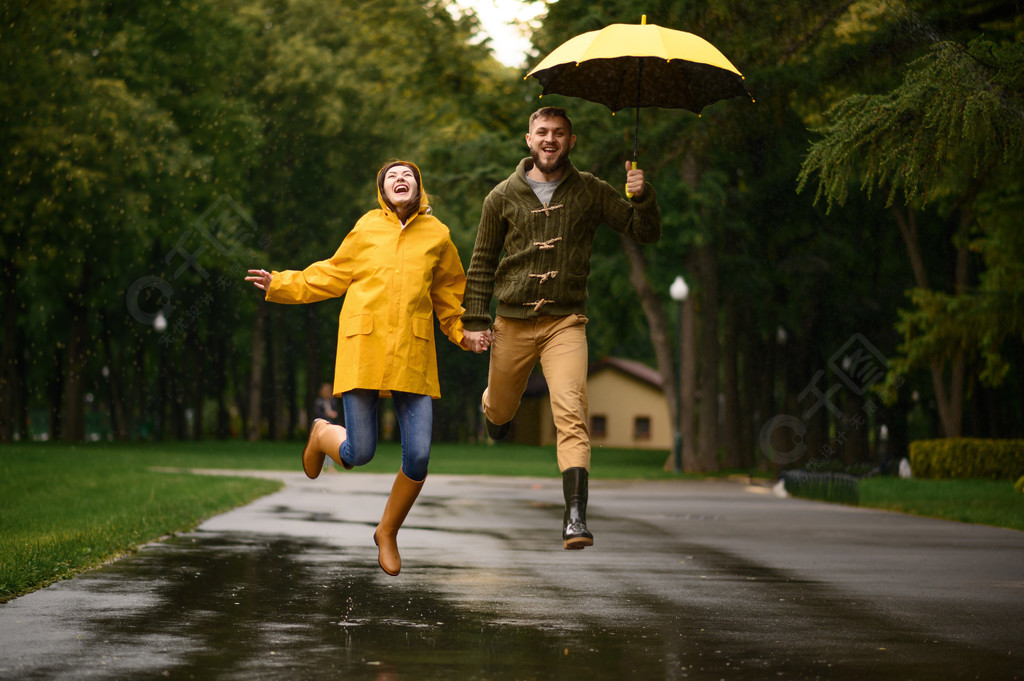幸福的爱情情侣跳像一个孩子在公园里夏天的雨天男人和女人在雨中的