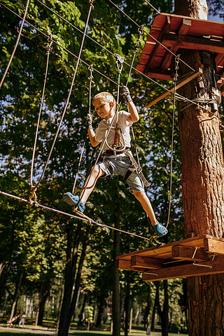 小男孩在绳索公园,操场的登山人上升儿童攀登吊桥,极限运动冒险度假