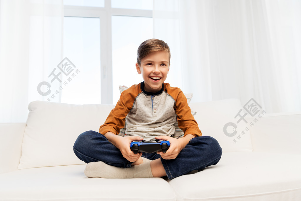 游戏,技术和人的概念—有在家打电子游戏的gamepad的微笑的男孩