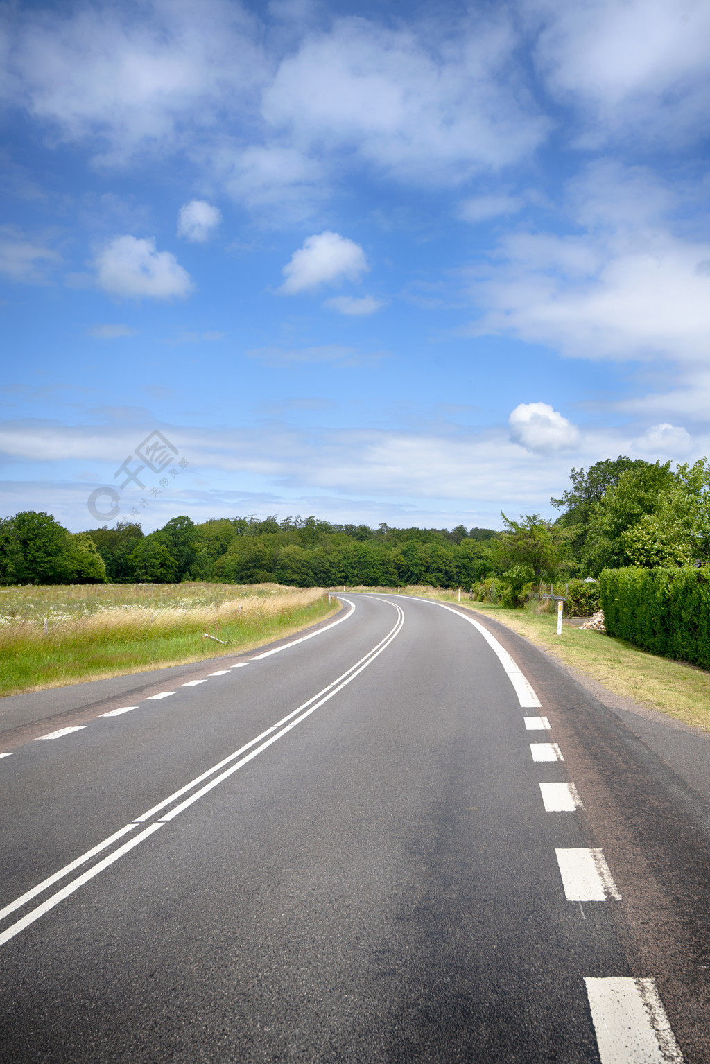 弯曲的道路,在农村的乡村景观,在夏天的蓝天下