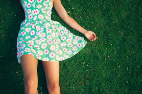 一个穿着花裙子的年轻女子在夏天躺在草地上