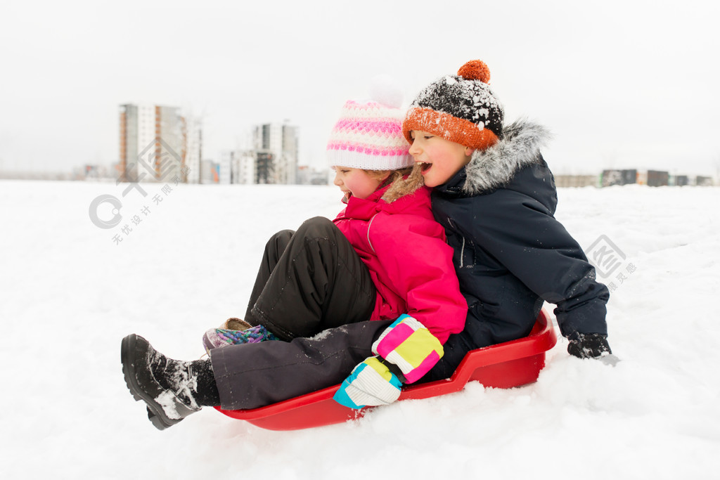 滑在雪撬下來雪小山的愉快的小孩在冬天小孩子在冬天在雪橇上滑下山