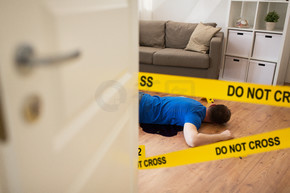谋杀案和犯罪现场的概念-尸体躺在警察磁带在家围起来的地板和子弹套上的地板上的血液房间里（舞台照片）犯罪现场地板上血液中的尸体尸体