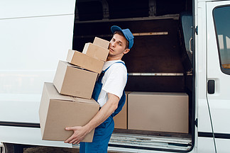 穿制服的邮递员用包裹，送货服务将汽车卸货男子站在车辆，男性交付，快递或运输工作的纸板包装
