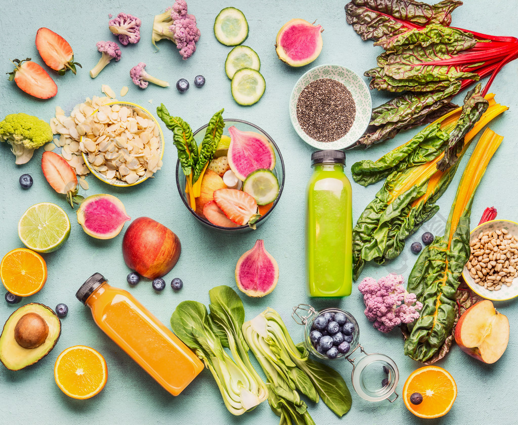 在桌上的绿色和黄色圆滑的人瓶与各种各样的新鲜的素食主义者成份和搅拌器，顶视图，平的位置健康的生活方式的概念干净的食物节食和排毒营养
