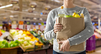购物，健康饮食和生态友好的概念— —关闭纸袋装满了在超市背景下的食物的女人纸袋装满食物的女人的特写